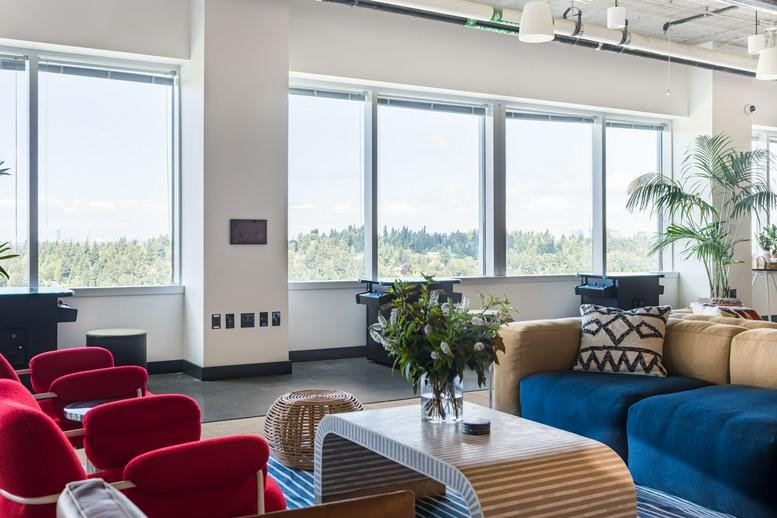Bright breakout lounge at 3120 139th Avenue Southeast with red armchairs and a blue sectional sofa.