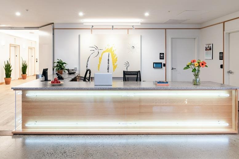 Modern lobby and front desk at 400 Capitol Mall, Sacramento, CA, California featuring warm wood and bright lighting.