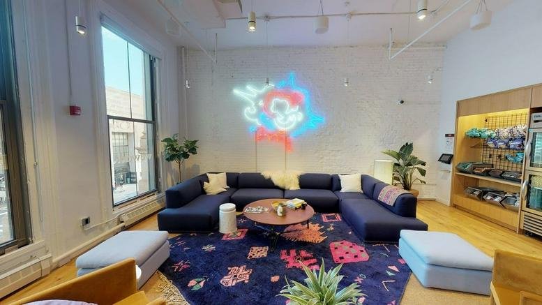 Spacious communal lounge at 408 Broadway, New York City with a navy sectional sofa and colorful patterned rug.