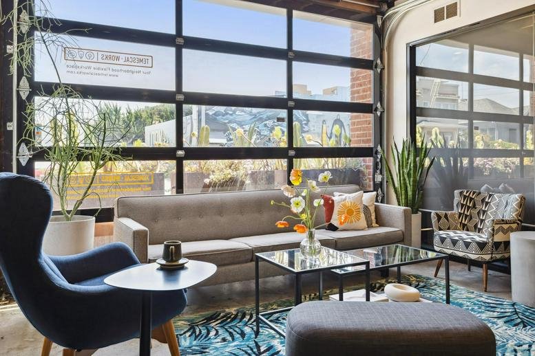 Bright sunlit lounge area at 490 43rd Street, Temescal District, Oakland with large glass garage door and plush seating.