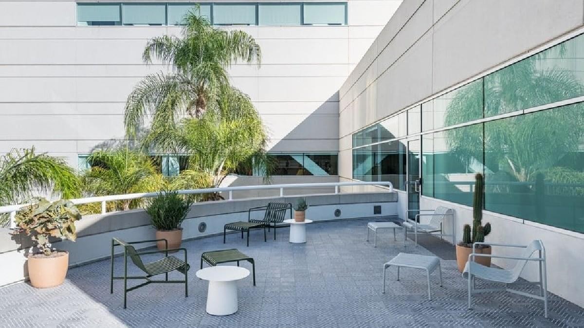Sunny outdoor terrace with modern seating and palm trees at 5161 Lankershim Boulevard.