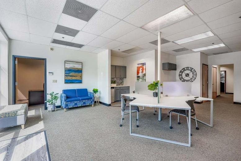 Bright coworking area with white shared desks, blue sofa, and skylights.
