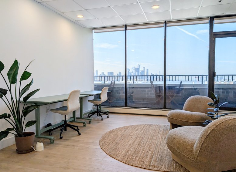 Sunlit lounge and workspace with floor-to-ceiling windows overlooking the city skyline.