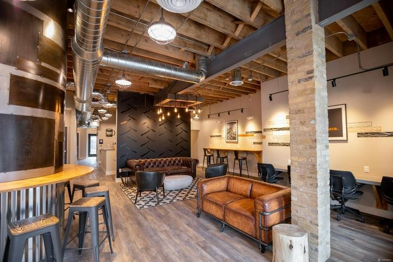 Lounge area at 7311 West Greenfield Avenue with leather sofas, exposed brick, and industrial ceilings.