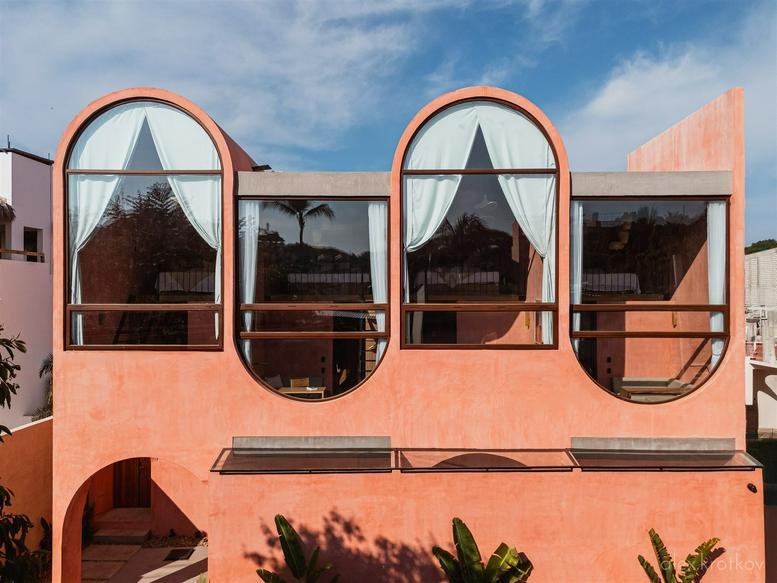Exterior facade of Amplitude Coliving with arched windows and terracotta walls.