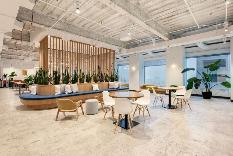 Spacious communal lounge with a curved blue bench, potted snake plants, and café seating at Wells Fargo Center.