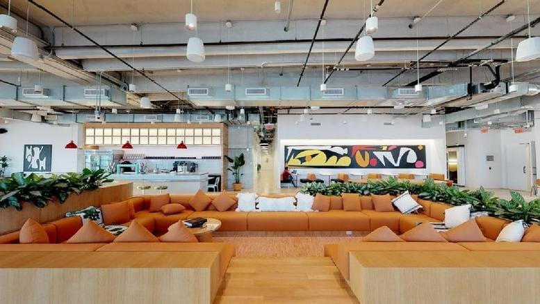 Spacious communal lounge with orange tiered seating and modern art at Wynwood Garage.