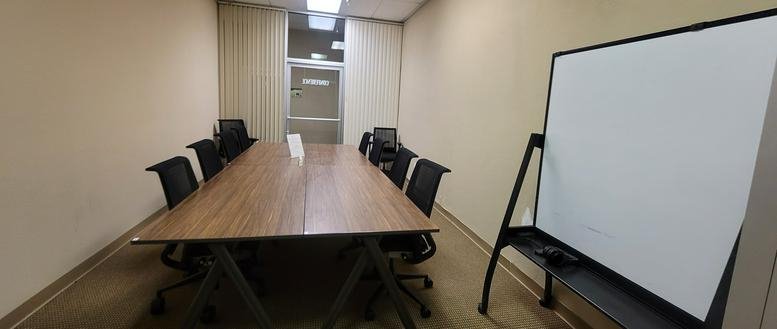 Meeting room at 2311 North Tracy Boulevard Suite A featuring a long wood-finish table and whiteboard.