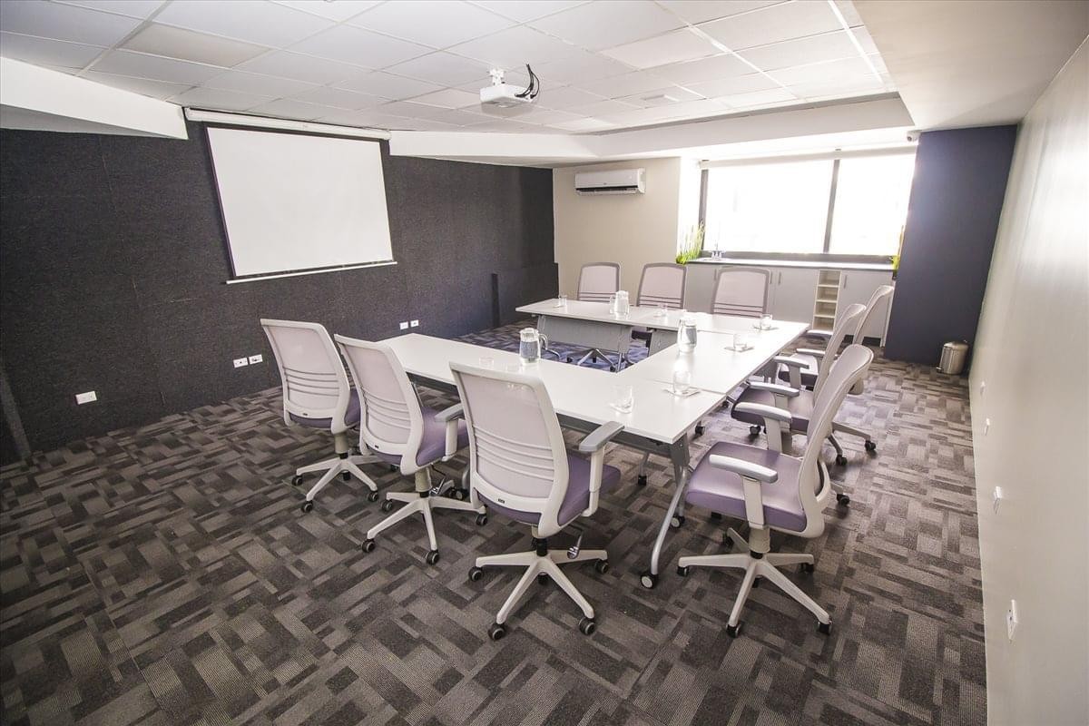 Modern conference room at 7 Avenue 9-64 Z. 9 featuring a U-shaped table and projection screen.