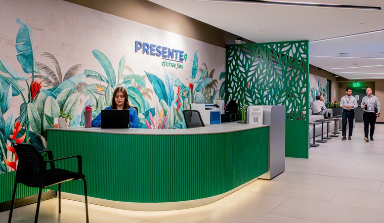 Green branded reception desk at Ruta Nacional Treciaria 310 with tropical wall art and bright lighting.