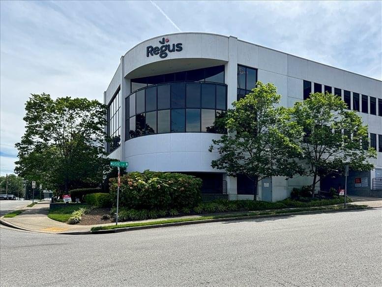 Wide street view of the modern white office building facade under a clear blue sky.