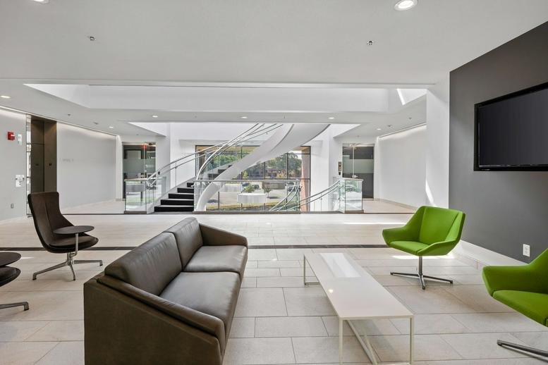 Bright lobby lounge area with green accent chairs and a sleek grey sofa.
