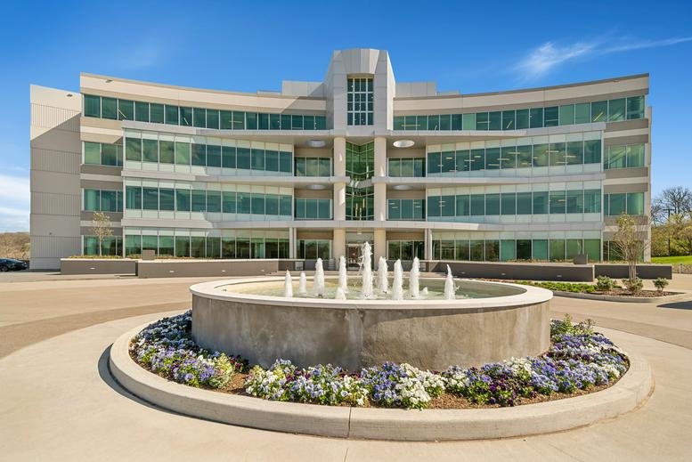 Exterior view of the multi-story curved glass building at 10 Burton Hills Boulevard.