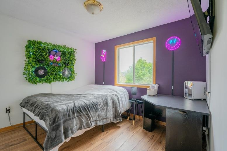 Modern bedroom with a purple feature wall and green wall art.