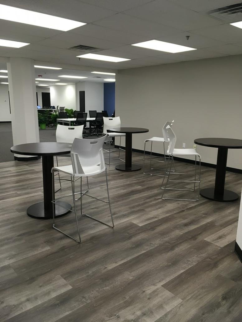 Spacious coworking area at 100 Cummings Center, Suite 109D with high-top tables and white stools.