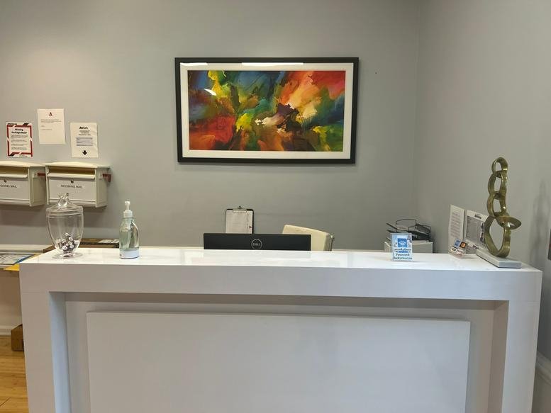 Bright reception desk at 10001 Derekwood Lane featuring colorful abstract artwork and a sleek white counter.