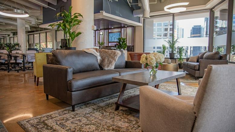Cozy breakout area with a brown leather sofa, patterned rug, and large windows at 1001 Wilshire Boulevard.