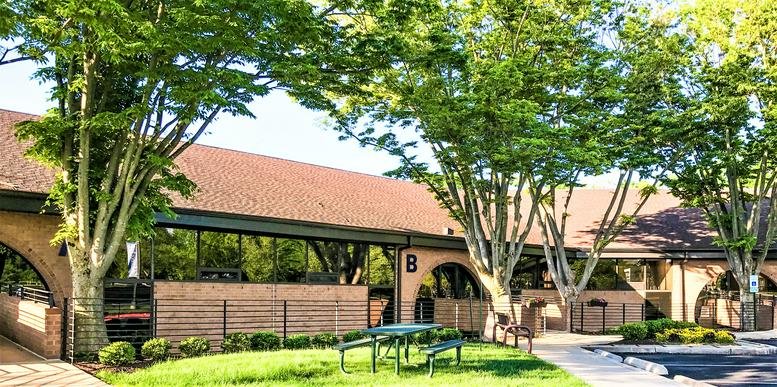 Exterior view of the brick building at 10015 Old Columbia Rd surrounded by lush green trees.