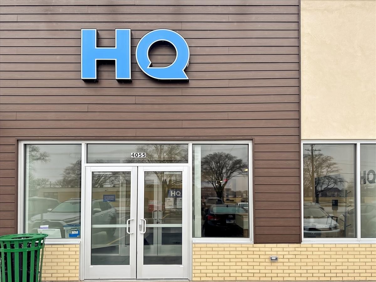 Exterior entrance of 10334 Route 59 with wood siding and a blue HQ sign.