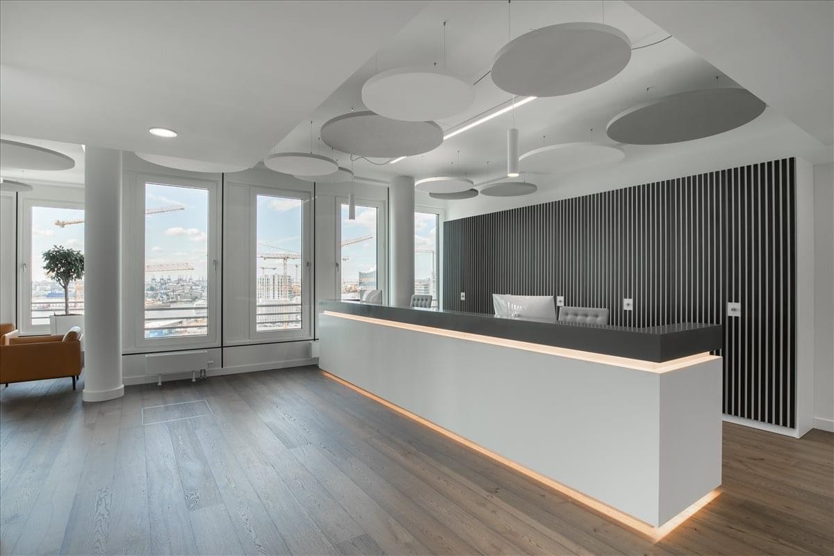 Spacious reception area with a minimalist white desk and circular acoustic ceiling panels at Star Metals Office.