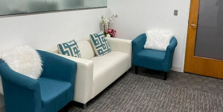 Bright reception area at 10630 Little Patuxent Parkway, Suite 314 featuring teal armchairs and a white sofa.