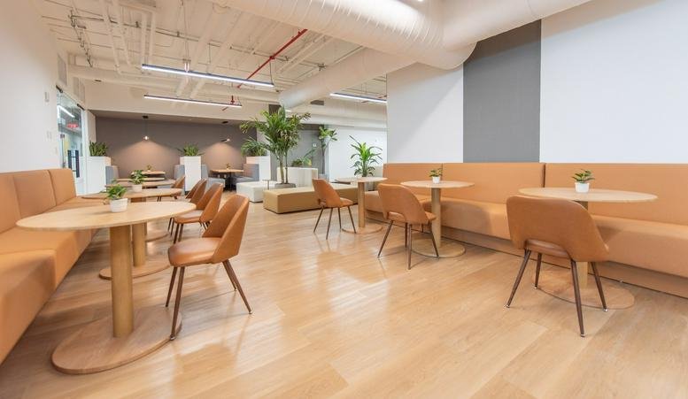 Spacious communal lounge at Panorama Tower with warm wood floors and tan booth seating.
