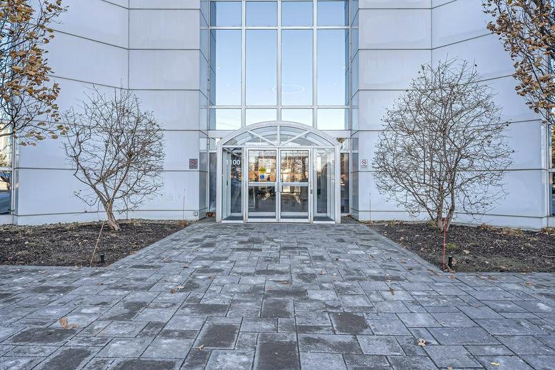 The glass entrance and stone walkway at 1100 Burloak Drive, Suite 300.