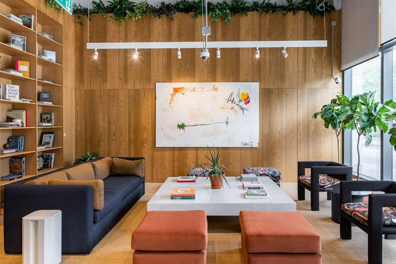 Spacious communal lounge at 1100 King Street West featuring wood-paneled walls and a large abstract painting.