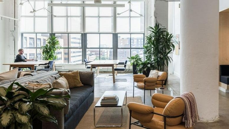 Spacious sunlit lounge at 1100 Ludlow Street featuring modern seating and large industrial windows.