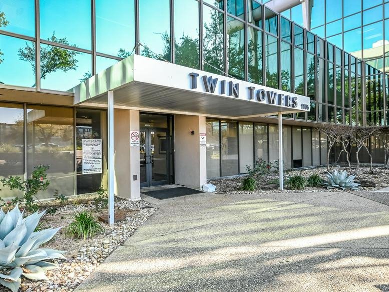 Main entrance of the glass office building with a Twin Towers sign above the door.