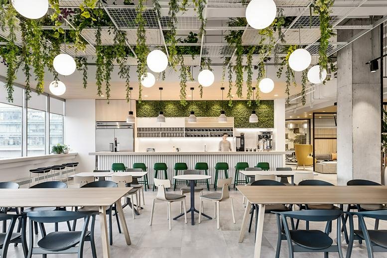 Spacious communal cafe area at 111 Peter Street, Suite 700 with hanging plants and globe pendant lights.