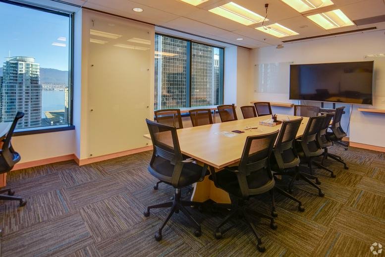 Professional boardroom with a long wooden table and panoramic city views.