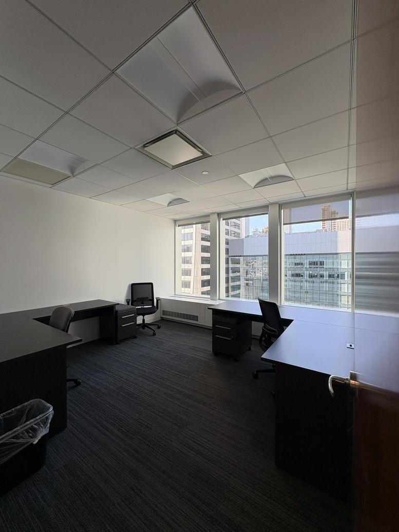 Spacious corner office at 1120 Avenue of the Americas with multiple desks and expansive city views.