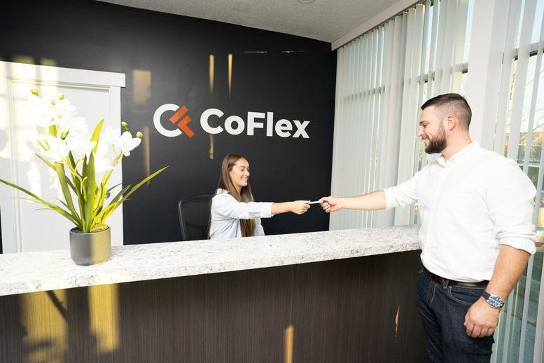 Reception desk at 1122 40th Avenue North East showing the CoFlex logo and a visitor being greeted.