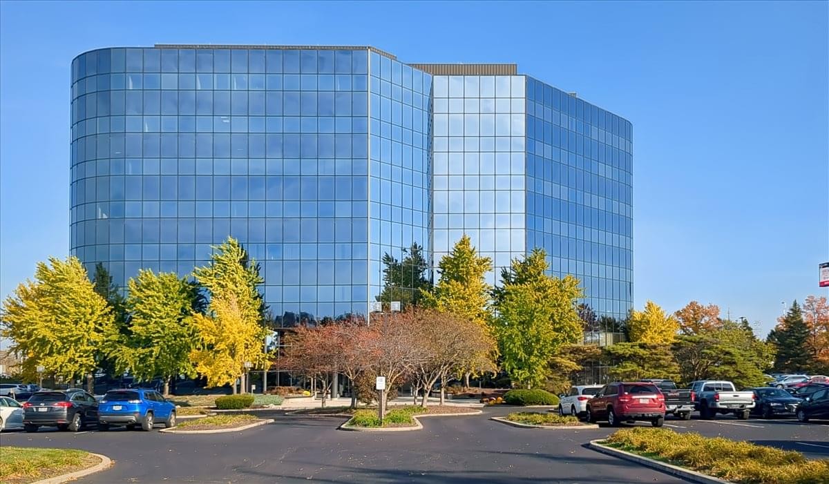 Exterior view of the glass-facade 11260 Chester Road office building with autumn trees.