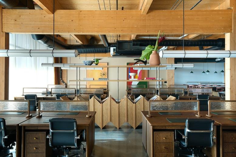 Modern open-plan office with timber beams and partitioned wooden desks.