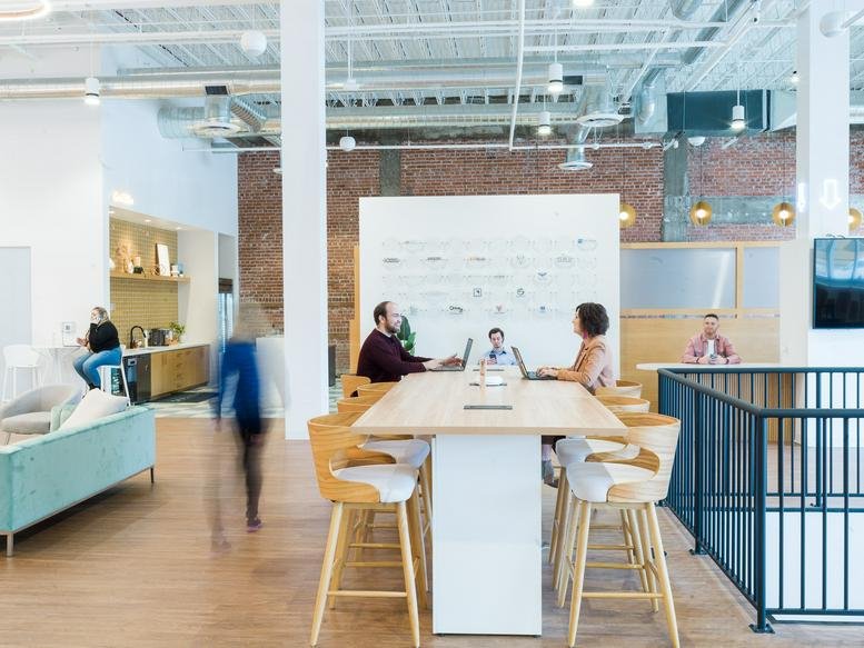 Spacious communal coworking area at 114 West Main Street, Newberry Station with high tables and brick accents.