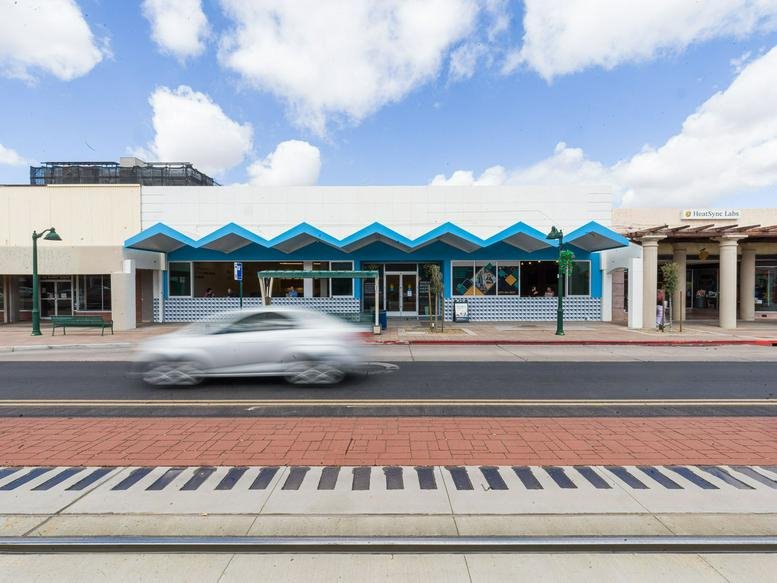 Exterior view of the white facade and blue zigzag awning at 114 West Main Street, Newberry Station.