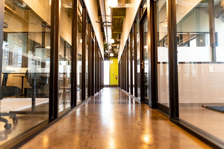 Long office corridor at 1165 North Clark Street with glass-walled suites and polished concrete floors.