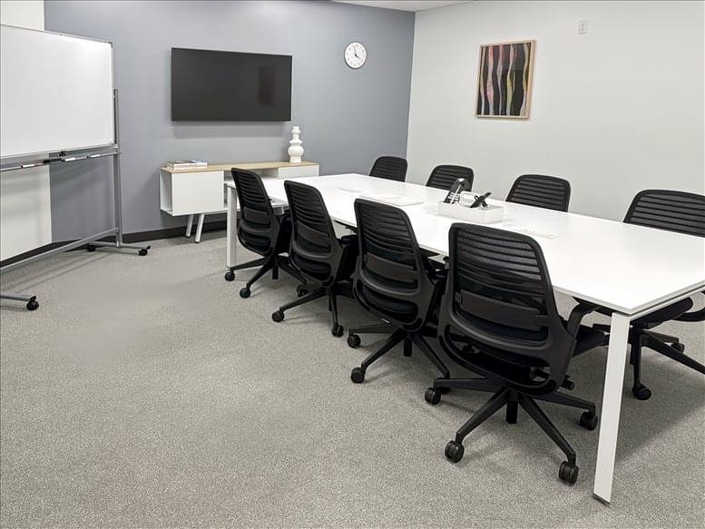Conference room with a large white table and black chairs.