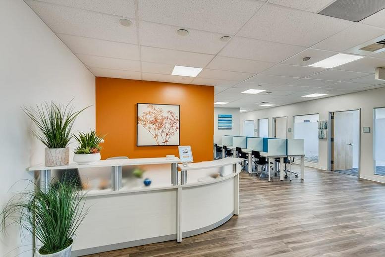 Bright lobby with orange accent wall and white reception desk at Metro North Building, Suite 550.