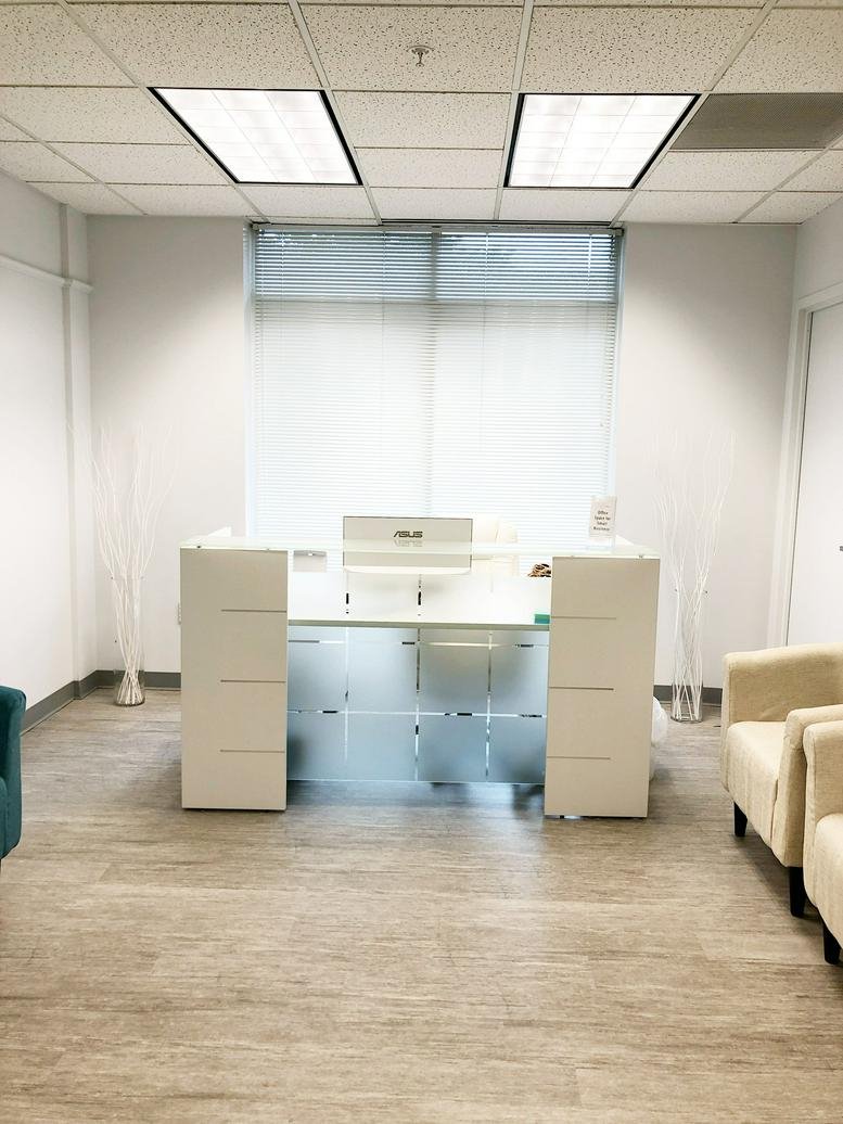Reception area at 12 South Summit Avenue, Suite 100, Gaithersburg, Maryland with modern white desk and glass panels.