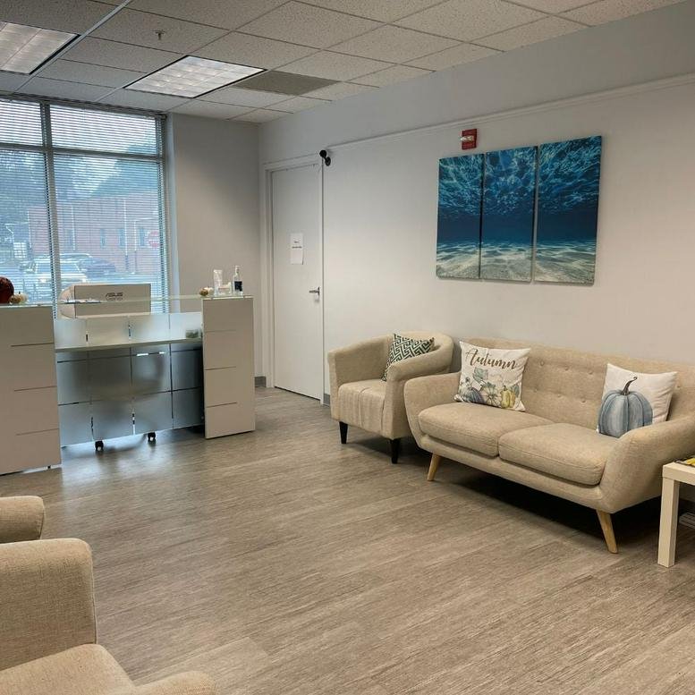 Modern lobby area at 12 South Summit Avenue, Suite 100, Gaithersburg, Maryland featuring a tan sofa and artwork.