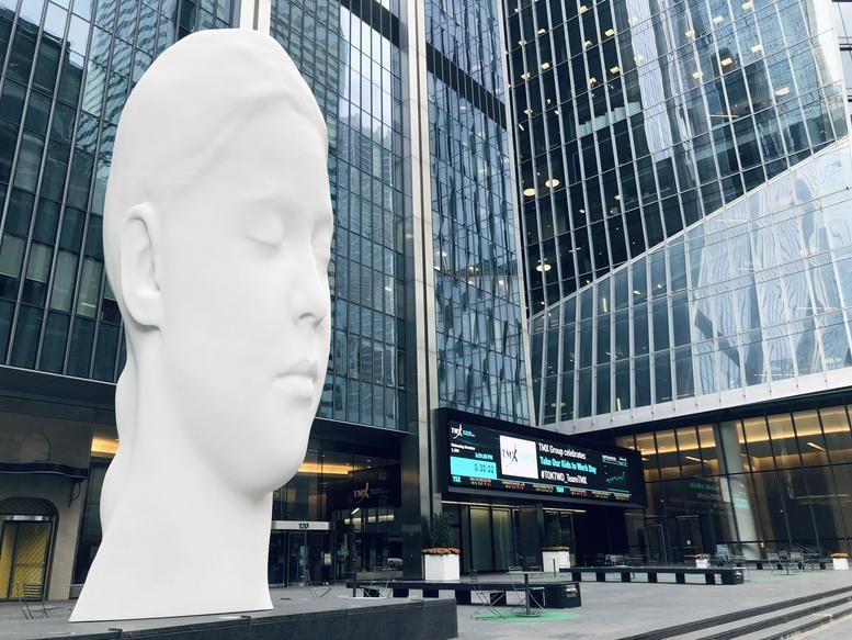 White sculpture in a plaza surrounded by modern skyscrapers.