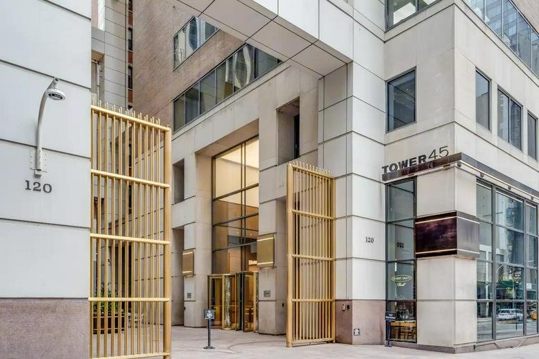 Main entrance of Tower 45 featuring tall gold gates and a clean stone facade.
