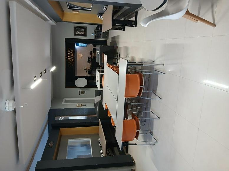 Large training room with rows of white tables and orange chairs.