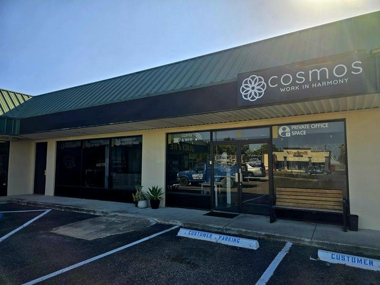 Exterior facade of the Cosmos Workspace building showing the entrance and parking lot.