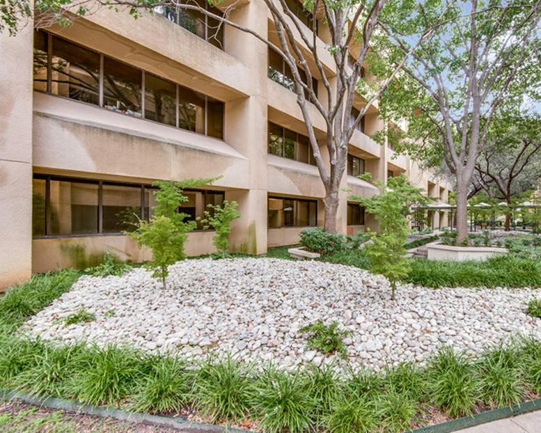Exterior facade of the tan multi-story building at 12000-12100 Ford Road with rock landscaping.