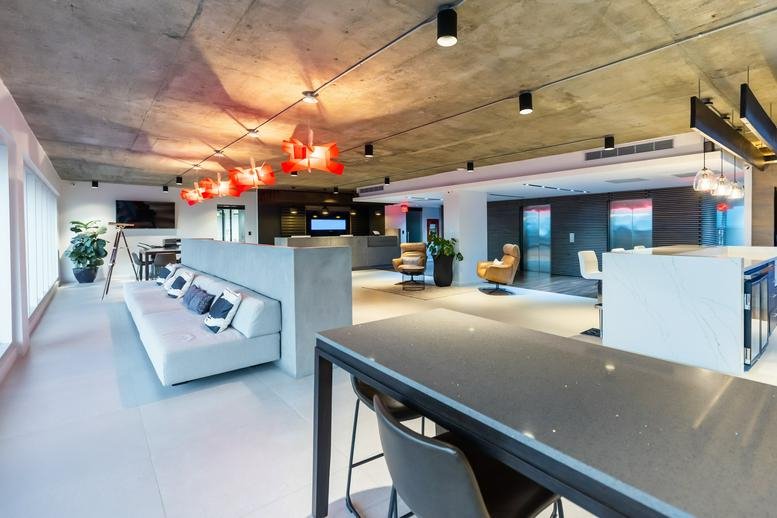 Spacious communal lounge at 1225 Avenida Juan Ponce de León, Penthouse with concrete ceilings and red light fixtures.