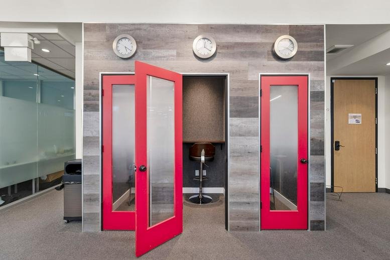 Hallway featuring vibrant red phone booths and wall-mounted analog clocks.